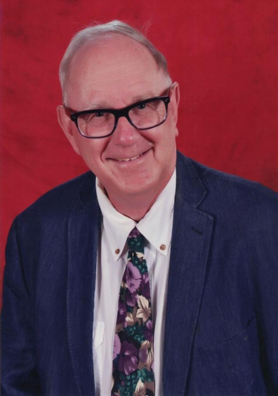 Dennis Frisch in a suit and tie, red background